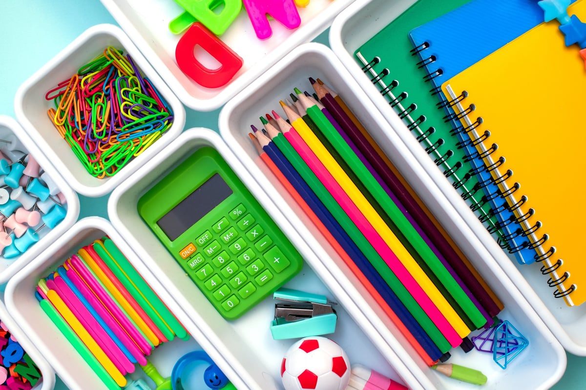 Artículos escolares de colores organizados en cajones blancos