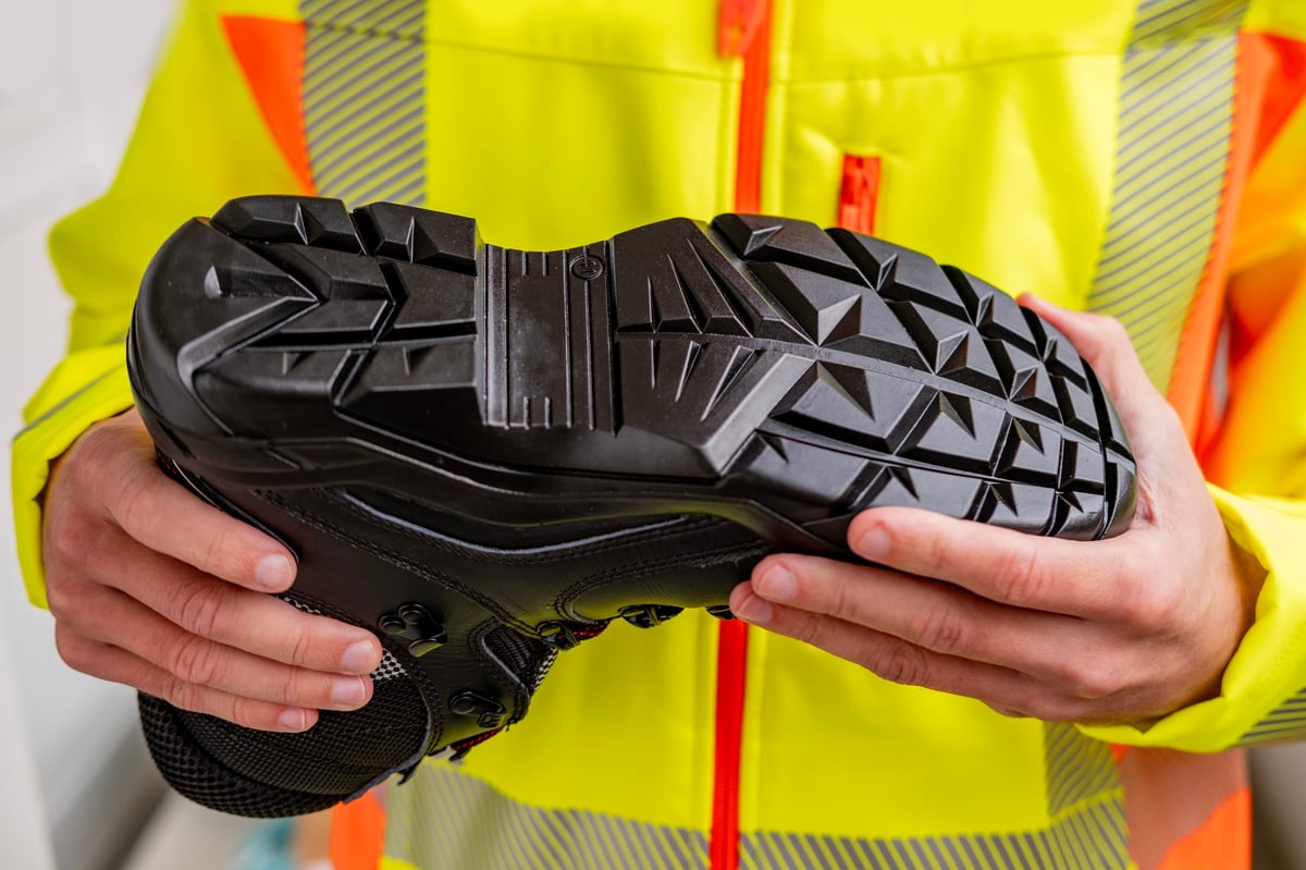Botas de seguridad industriales con casquillo de acero reforzado sostenidas por un trabajador