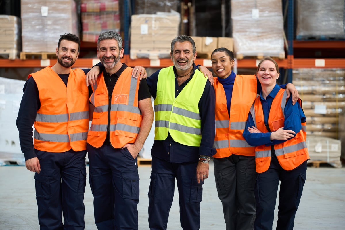 Grupo de trabajadores con chaleco y uniforme de trabajo en un almacén