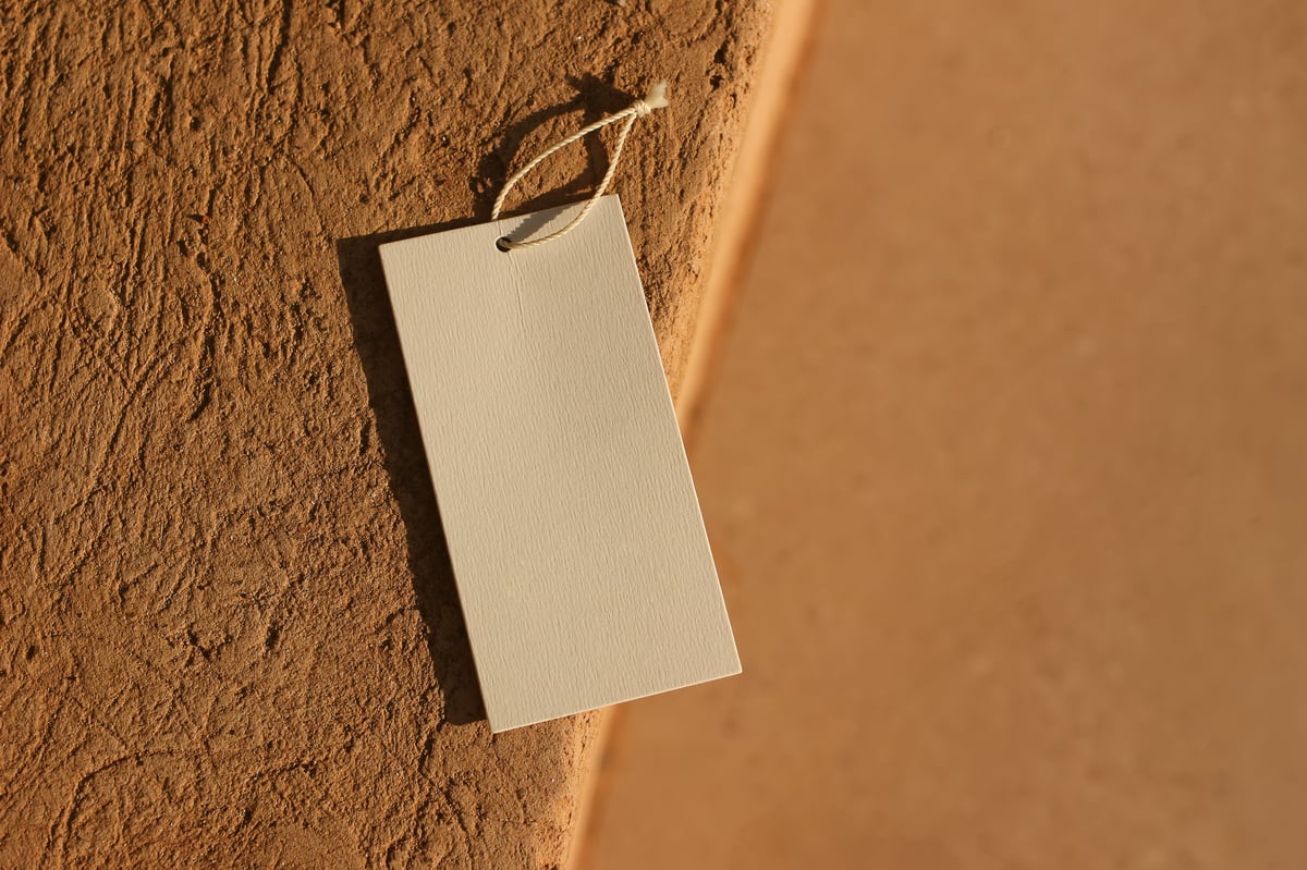 Etiqueta colgante de papel sobre un muro de barro, presentación de producto artesanal